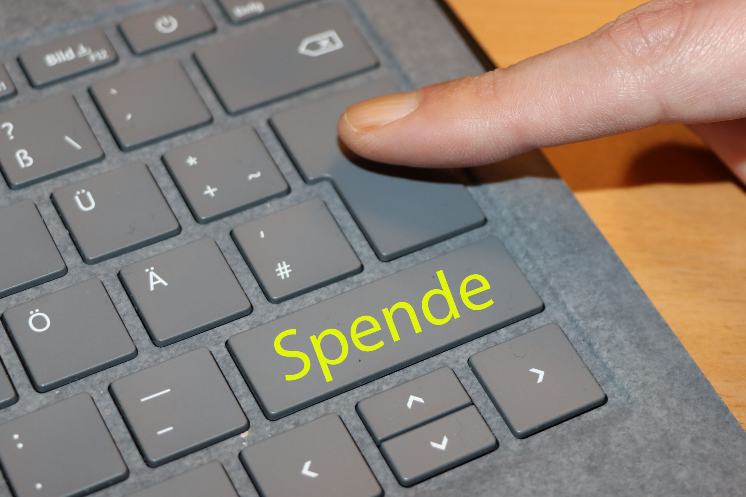 Tastatur mit Finger. Auf einer Taste steht Spende