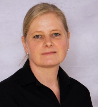 Anja Kuhnert: Eine Frau mit langen blonden Haaren mit Zopf. Sie trägt Ohrringe.