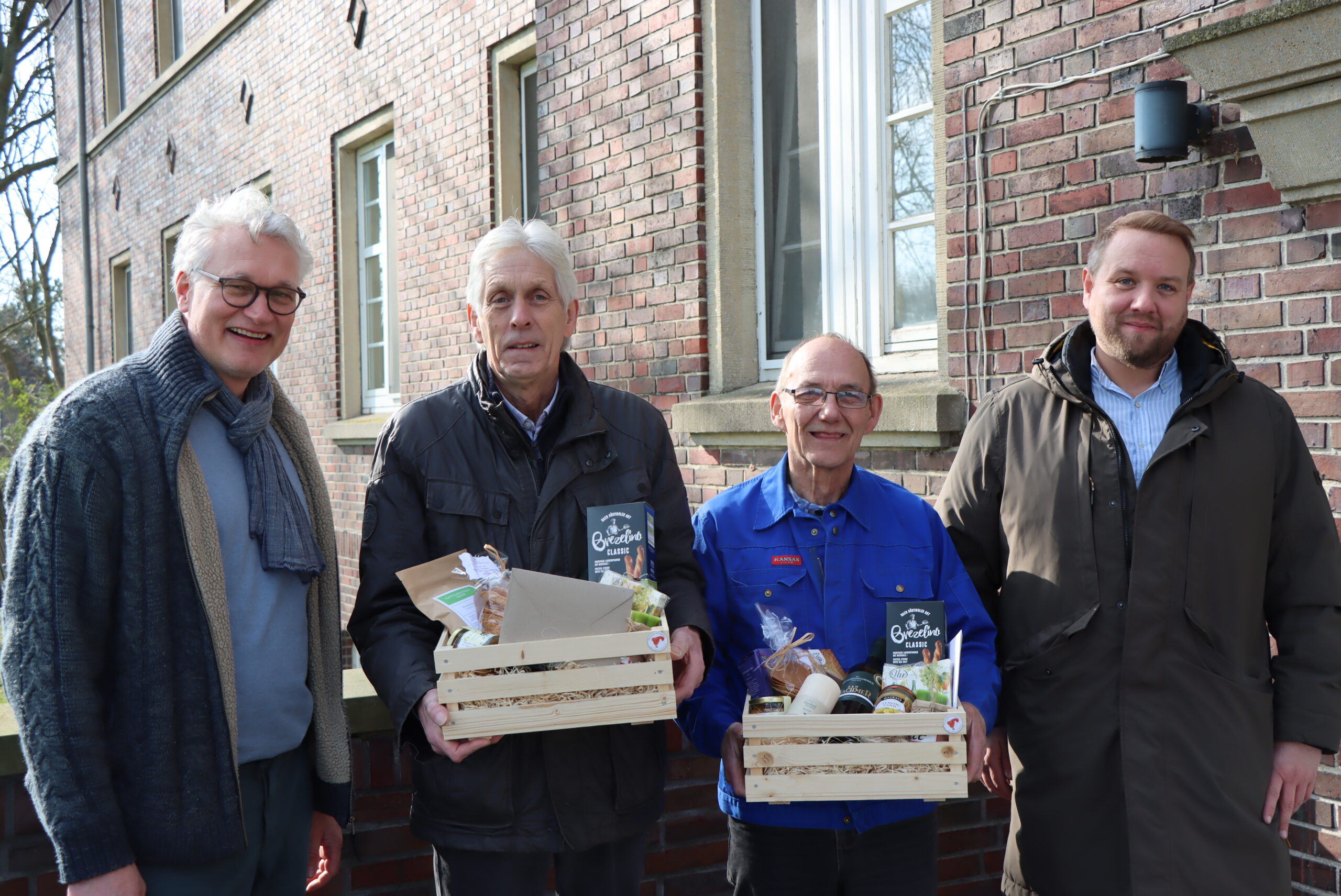 Zwei GPS Mitarbeiter und zwei Gäste bei einer Geschenkübergabe. Die zwei Gäste haben ein Präsentkorb bekommen.