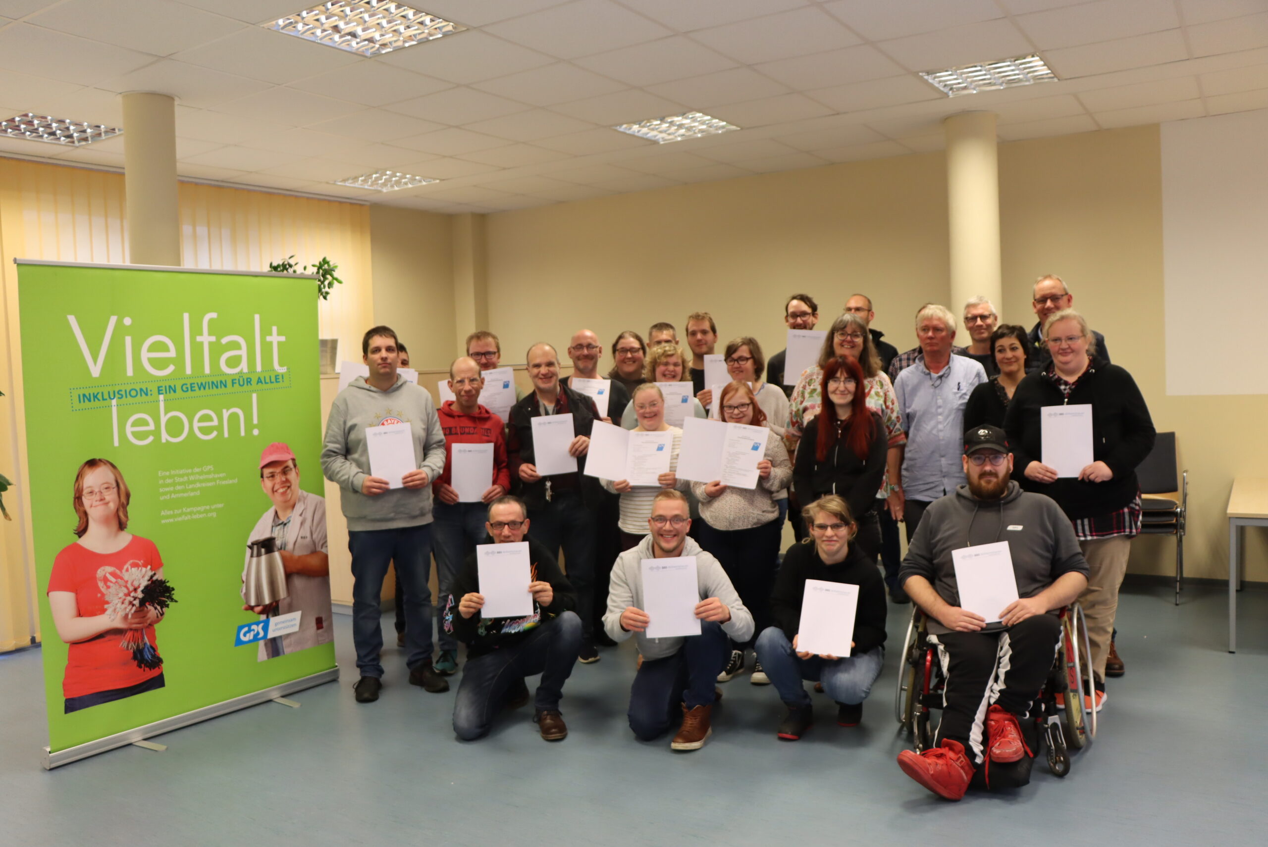 Die Jubliare vom Jahr 2023. Man sieht Menschen im dem Raum mit ihren Jubliarsurkunden und ein Roll-up "Vielfalt leben". Die Menschen sind Beschäftigte von der GPS.