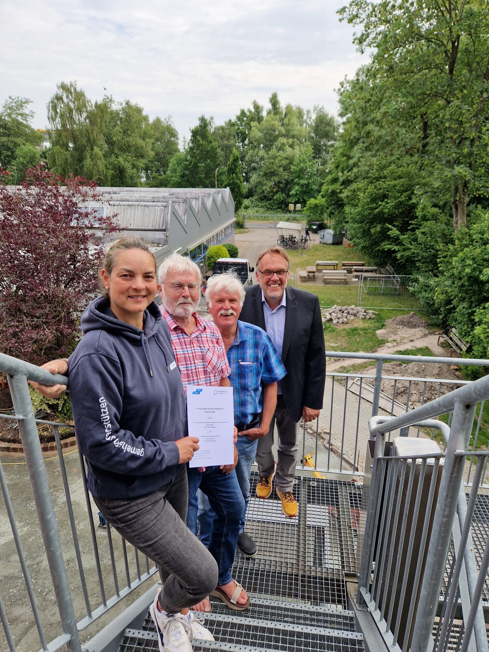 Draußen bei der Werkstatt Wilhelmshaven auf den Notreppen mit dem Geschäftsführer der GPS, Leiterin vom GPS Inklusionssport mit zwei älteren Männern