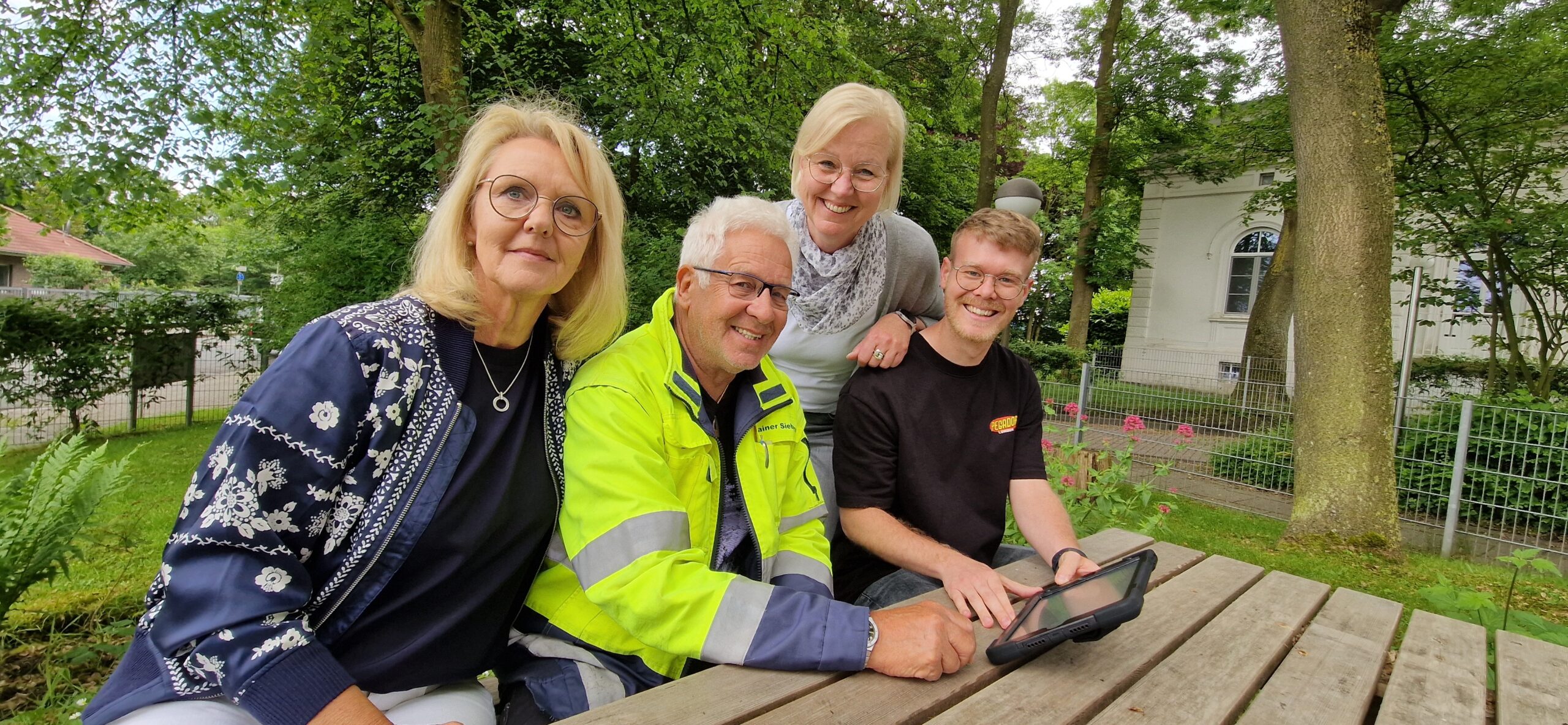 GPS Mitarbeiterinnen mit zwei Männern draußen im Garten am Tisch