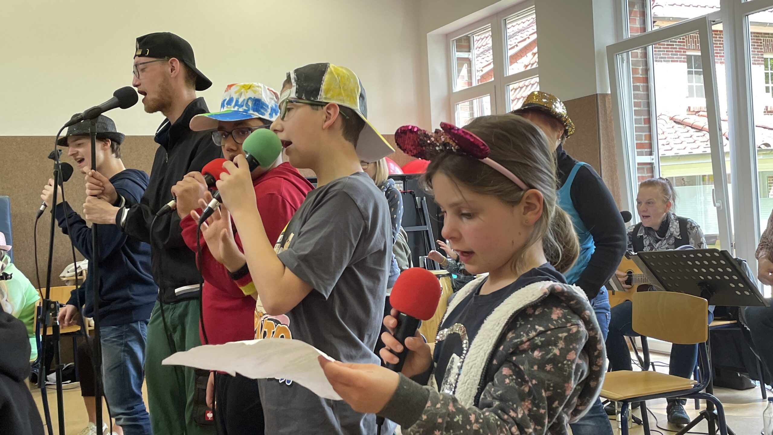 Kinder, Jugendliche und ältere Menschen singen und machen Musik in einem Raum