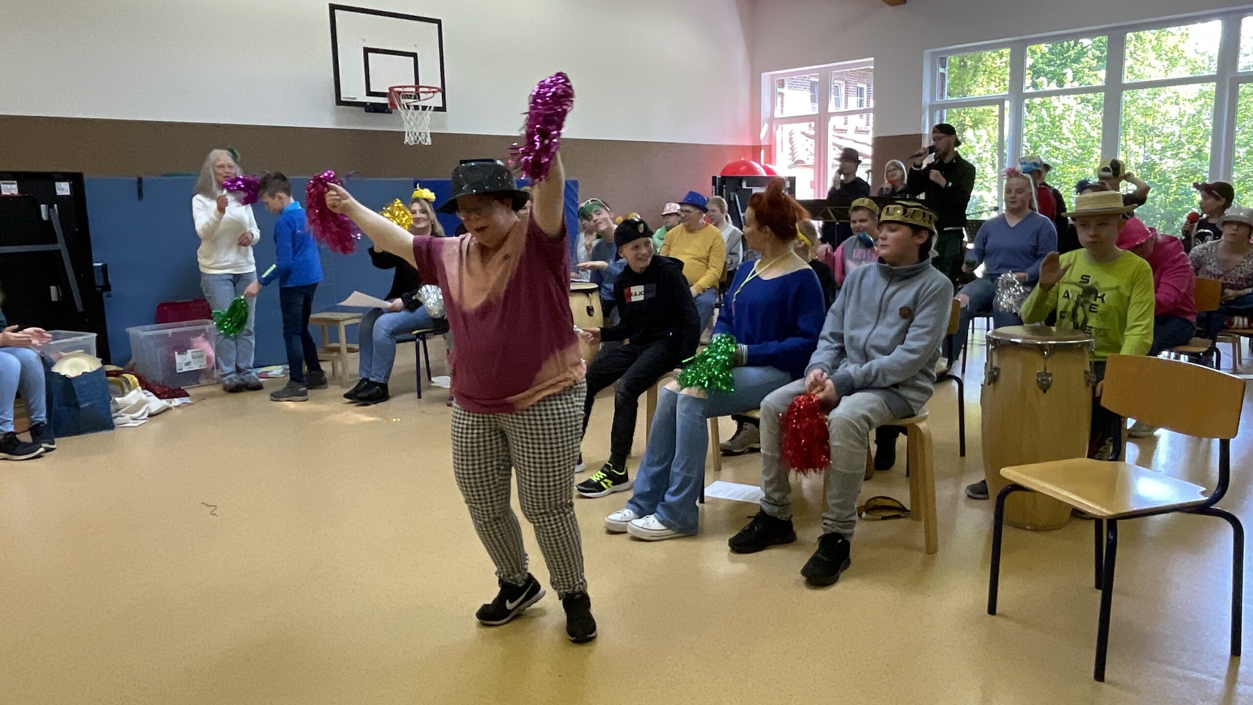 In einem Raum sitzen Menschen auf Stühlen oder stehen und schauen eine Frau beim Tanzen zu. Sie sind in einem Raum.