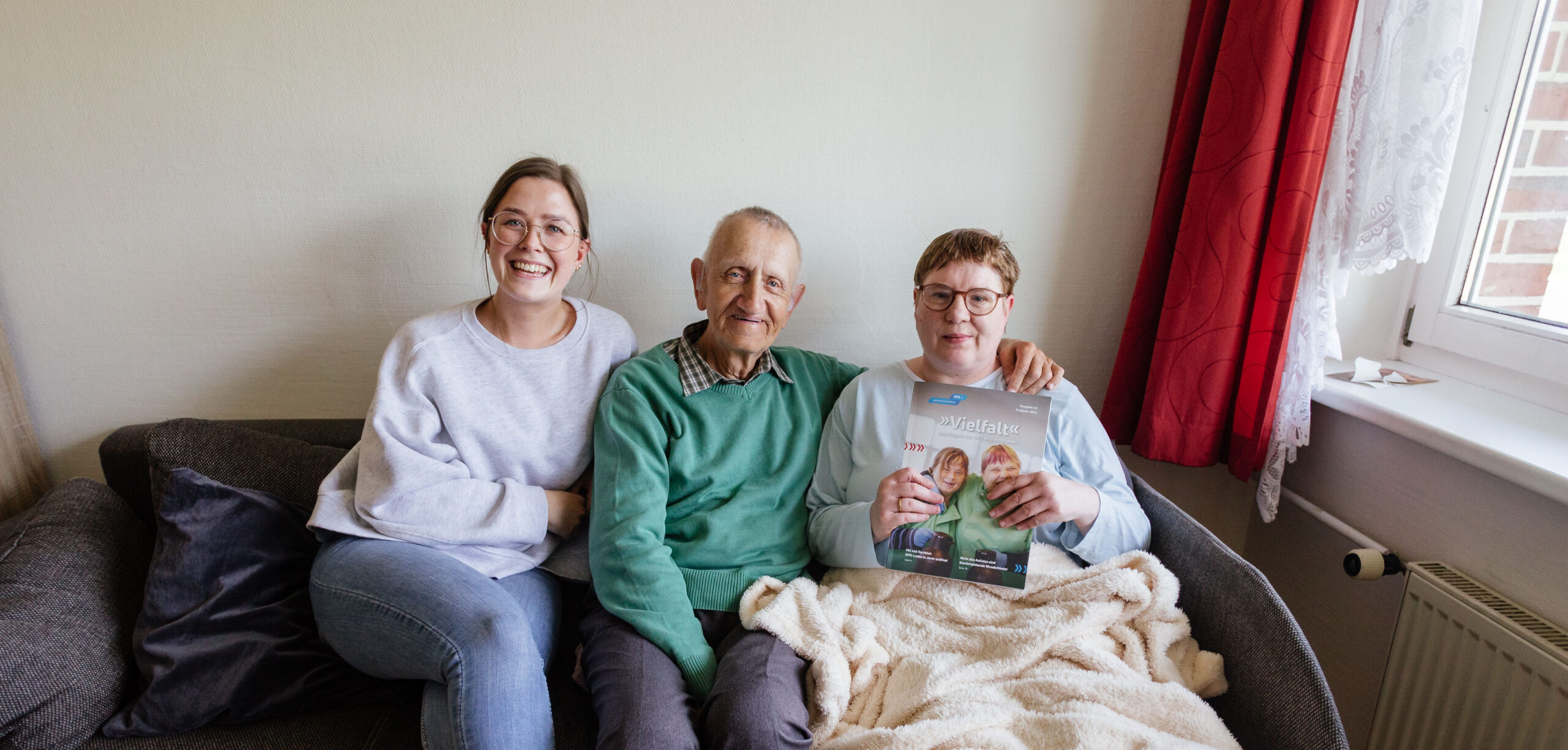Drei Menschen sitzen auf einem Sofa